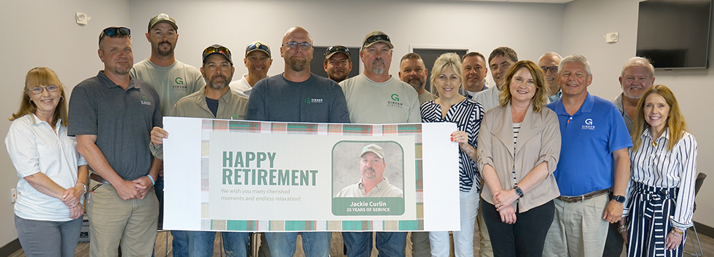 Several men and women stand, holding a sign that reads, "Happy Retirement," for Jackie Curlin, a lineworker who retired with 25 years of service to Gibson Electric.
